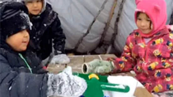Three kids sat at a table looking at a scale