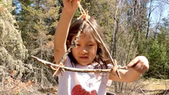 A kid holding a triangle made from twigs.