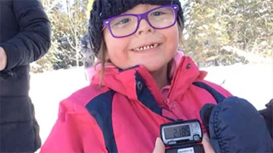 A kid smiling, holding a pedometer