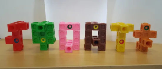 Colorful interlocking cubes arranged in abstract shapes on a wooden surface.