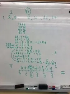 Green text and numbers written on a whiteboard.