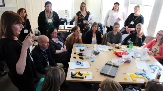 A group of people gathered around a table, engaging in an activity involving LEGO pieces.