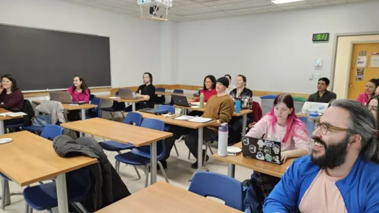 Students in a classroom working on laptops and notebooks.