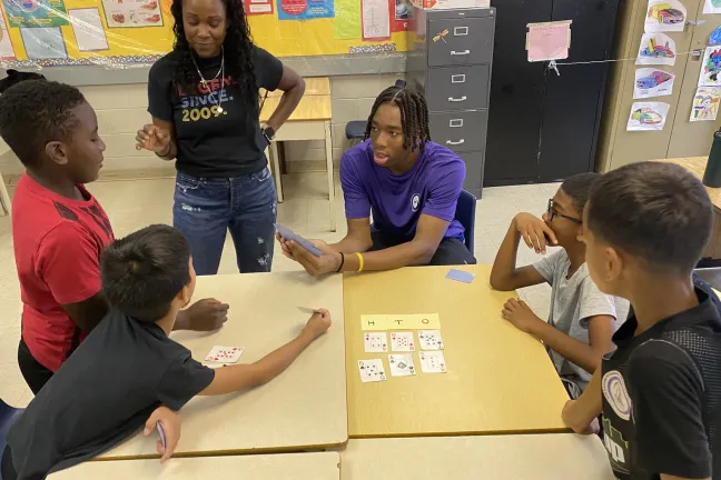 Two instructors playing cards with YAAACE students.