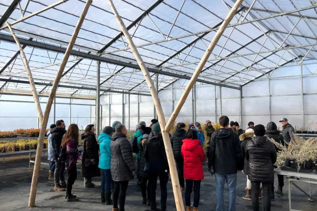 A group of people standing in a greenhouse.