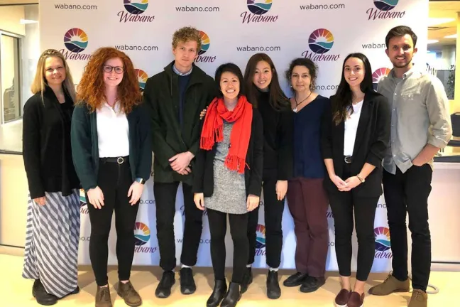 A group of people standing in front of a step and repeat banner.
