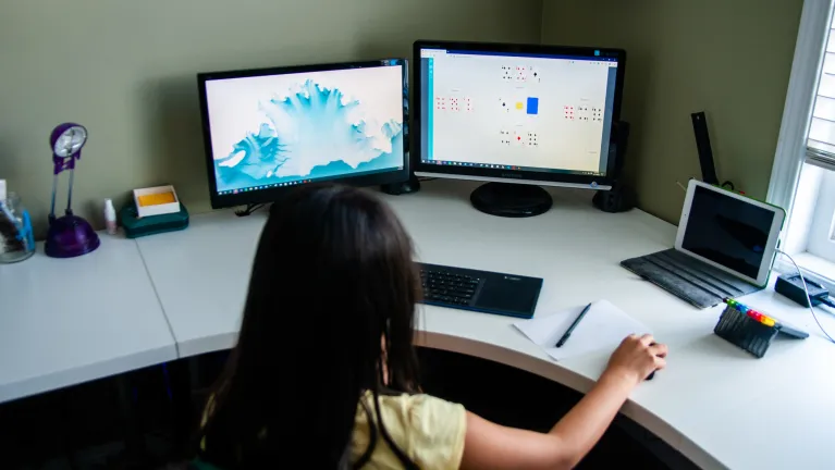A child looking at two computer screens.
