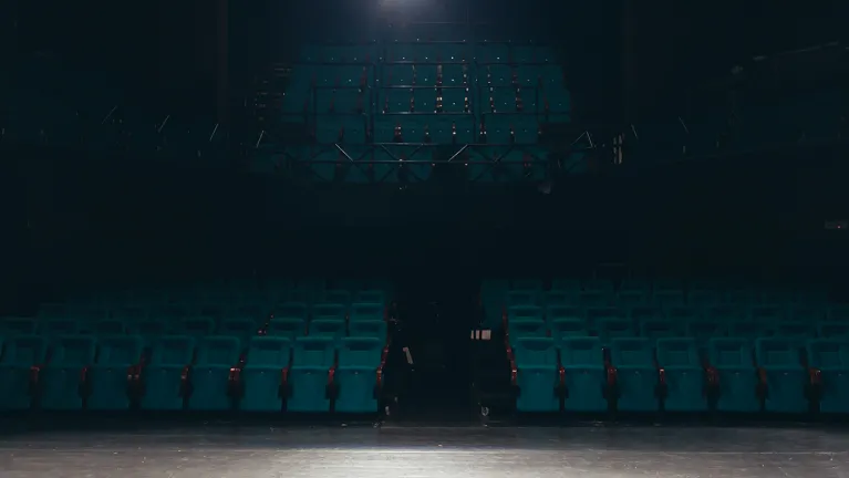 A view of empty theatre chairs from a stage.