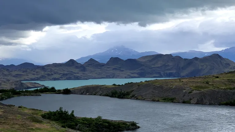 picturesque lake encircled by rugged mountains, with clouds drifting lazily overhead.